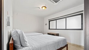 Un dormitorio con dos camas, una ventana y un respiradero en el techo.