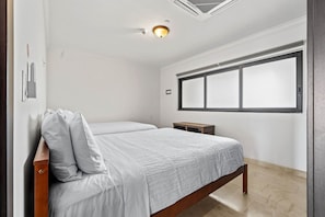 A bedroom with two beds, a window, and a ceiling vent. - Noord Paradise! 2BR Condo with Pool and Gym Access (Noord)