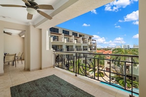 A balcony with a view of a residential area, a pool, and a dining area with chairs and a table. - Noord Paradise! 2BR Condo with Pool and Gym Access (Noord)