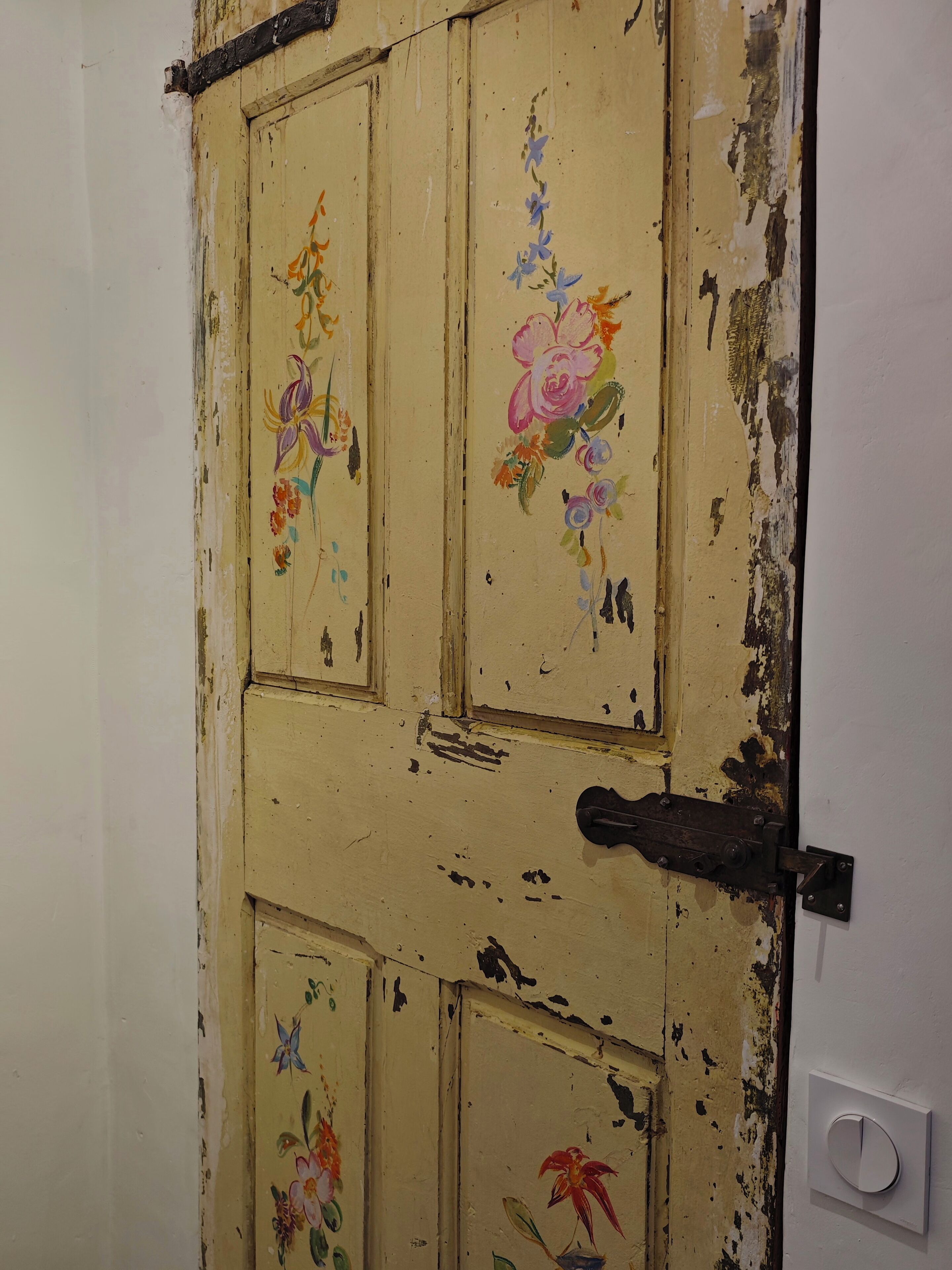 A worn door with floral artwork and a simple latch.