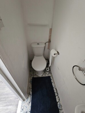 Un baño pequeño y estrecho con inodoro, toallero y piso estampado.
