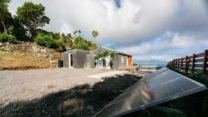 Solpaneler i et landligt område med en lille bygning og et træhegn.