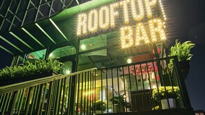 Een dakterras met een neonbord waarop 'ROOFTOP BAR' staat en een neonbord met de tekst 'NOSTALGIC'.