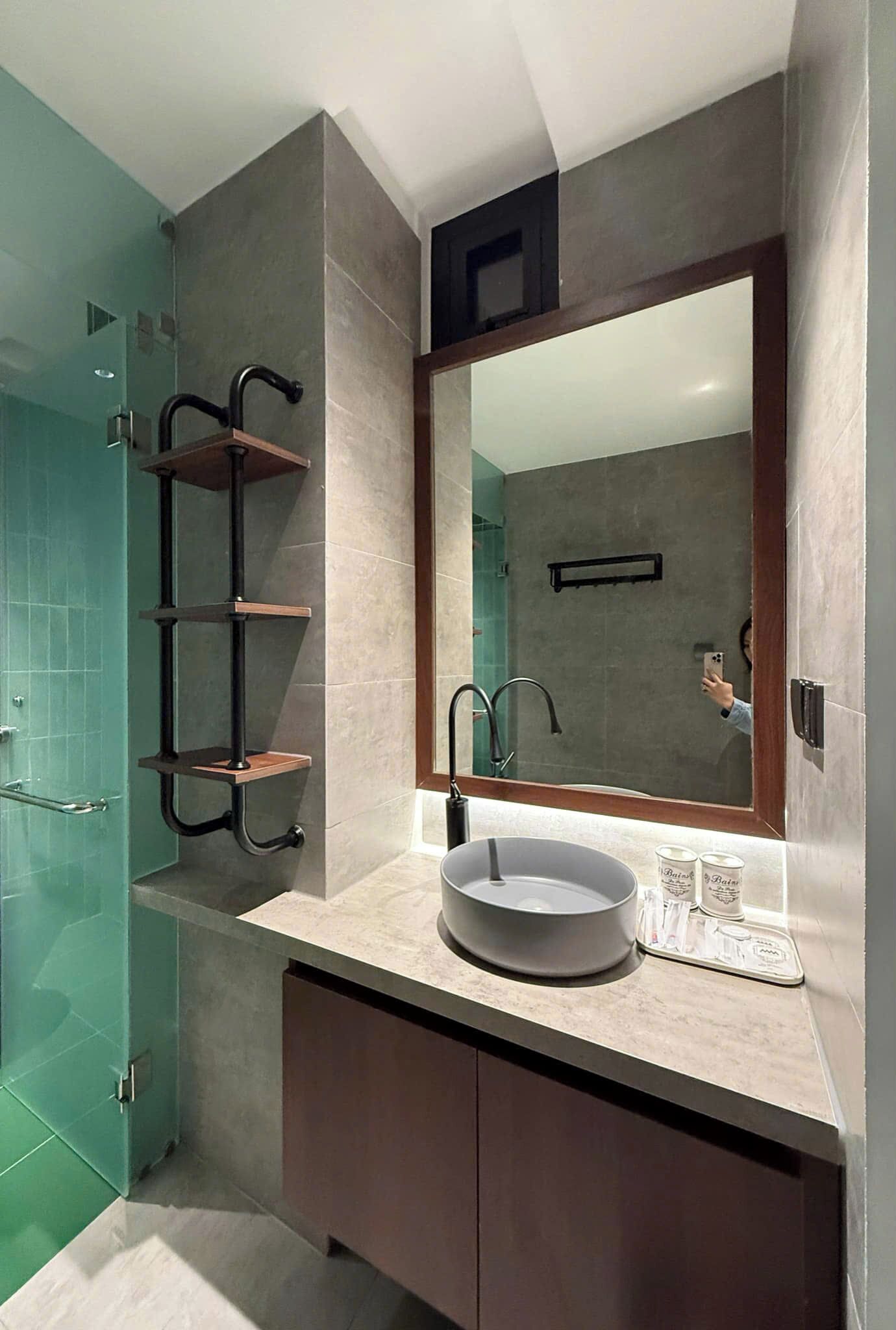 A modern bathroom with a large mirror, a round sink, and a glass shower enclosure.