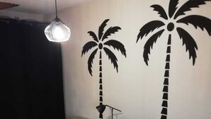 A bedroom with a bed, a desk, a chair, and a hanging light fixture. - Cosy apartment for curists or tourists (sleeps 2 to 6) (Saujon)
