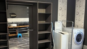 Une buanderie équipée d’un lave-linge, d’un étendoir et d’un tabouret.