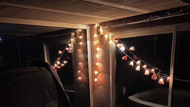 Une piscine gonflable décorée de guirlandes lumineuses, une cloison en verre et un fond sombre.