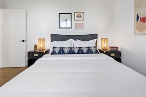 A bedroom with a bed, two bedside tables, a door, and wall decorations.