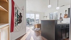 A modern kitchen with dark cabinets, a central island, and a view to the outside. - Pine at Evergreen - Boutique Hotel (Redding)