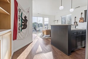 A modern kitchen with dark cabinets, a central island, and a view to the outside.