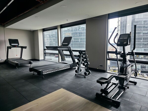 A gym with treadmills, dumbbells, and exercise equipment.