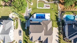 Vue aérienne d’un quartier résidentiel avec des maisons, une piscine et un court de tennis.