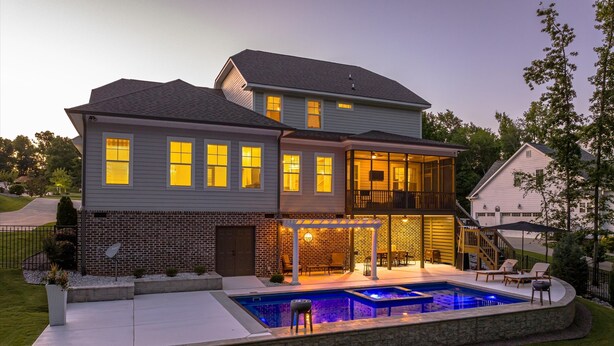 Une maison à deux étages avec une piscine et un espace extérieur aménagé pour se détendre.