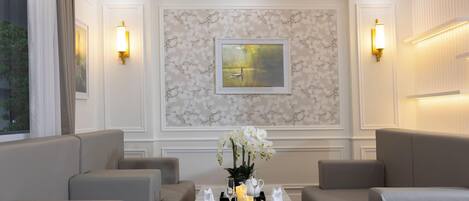 Un comedor con pared de mármol, una obra de arte enmarcada y dos lámparas fijadas a la pared.