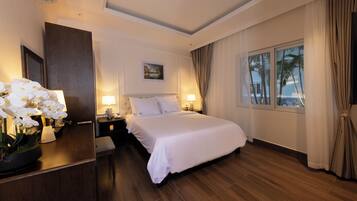 A hotel room with a large bed, bedside lamps, a nightstand, a mirror, and a window with curtains.
