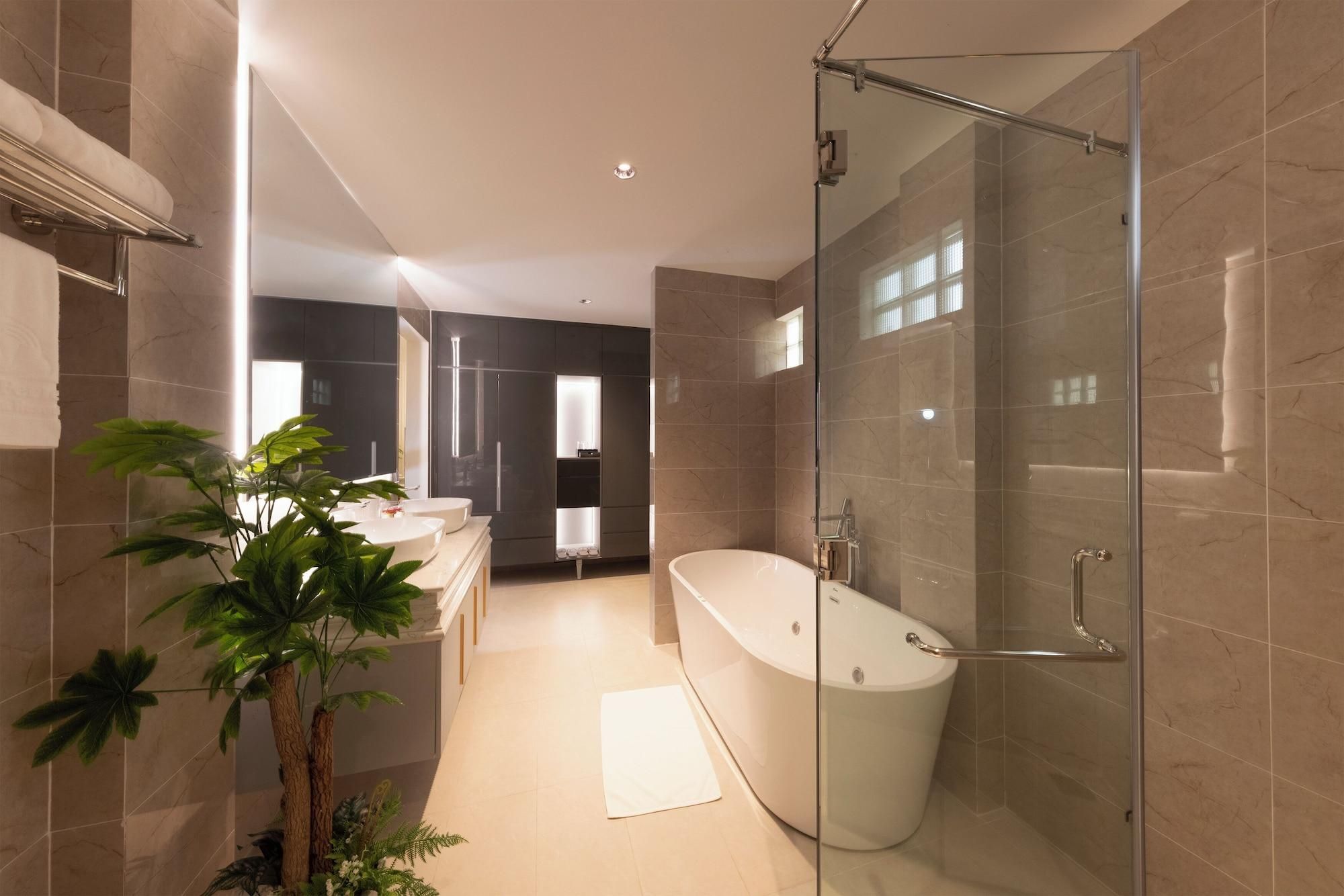 A modern bathroom with a freestanding bathtub, a glass-enclosed shower, and a large potted plant.