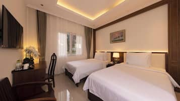 Habitación de hotel con dos camas, un escritorio con lámpara, una silla, una ventana con cortinas y un cuadro en la pared.
