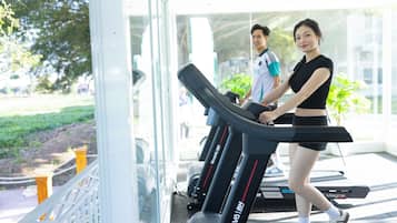 A gym with treadmills, a glass wall, and a view of a park.