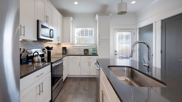 A modern kitchen with white cabinets, stainless steel appliances, and a large sink. - Beautiful Townhomes! Two Units With Outdoor Patios (Nashville)