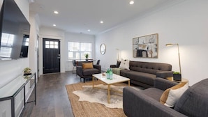 A modern living room with a sofa, coffee table, and a TV mounted on the wall. - Beautiful Townhomes! Two Units With Outdoor Patios (Nashville)