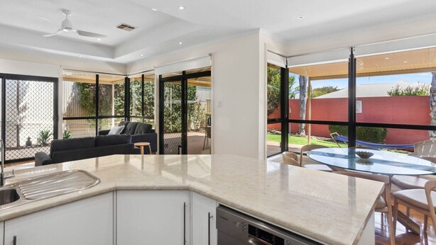 Una cocina moderna con lavavajillas integrado, un comedor con una mesa redonda y sillas, y una sala de estar con sofá y sillones.