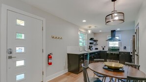 A modern kitchen with a dining area, featuring a central island, pendant lighting, and a fire extinguisher on the wall. - Cute And Cozy - Historic Franklin Quadplex (Franklin)