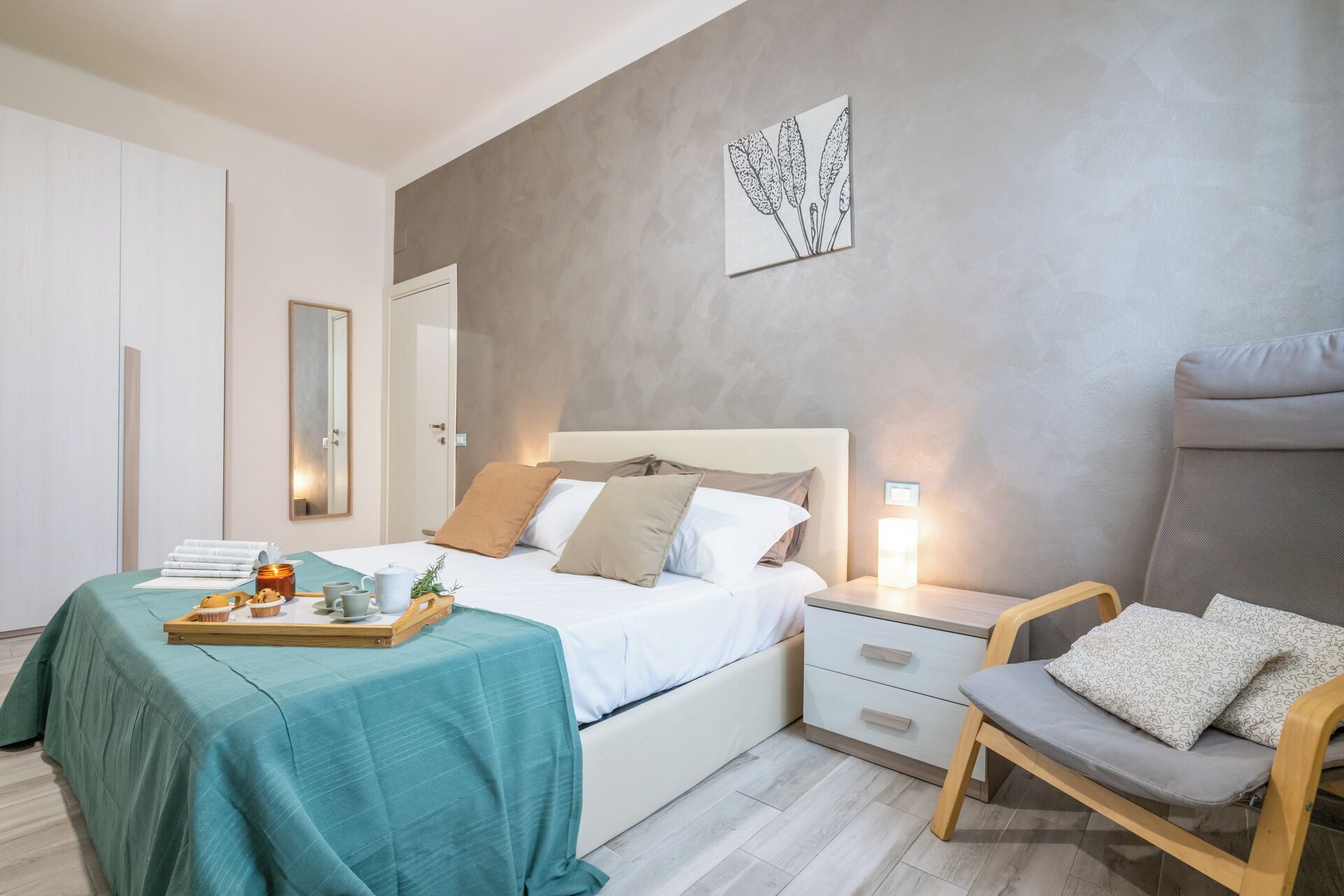 Un dormitorio moderno con una cama, mesita de noche, silla y una obra de arte colgada en la pared.