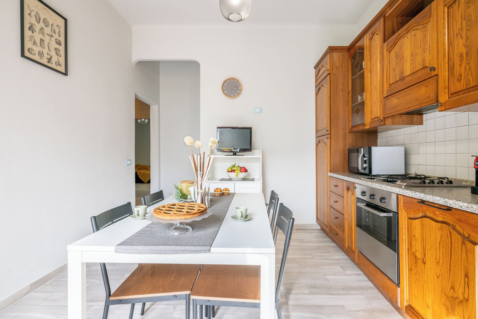 Cozinha moderna com armários de madeira, bancada branca e área de refeições com mesa e cadeiras.
