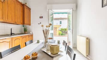 A kitchen with wooden cabinets, a white countertop, and a dining area with a table set for two.