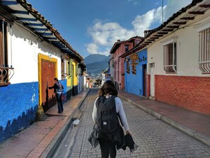 A narrow street with colorful buildings, a clear sky, and a distant mountain range. - Hotel Suite Centro Bogota (Bogotá)