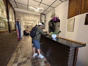 A hotel reception area with a reception desk, a potted plant, and a reception sign. - Hotel Suite Centro Bogota (Bogotá)