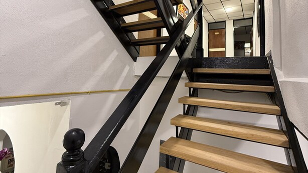 A spiral staircase with wooden steps and black metal railings. - Hotel Suite Centro Bogota (Bogotá)