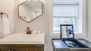 A bathroom with a white vanity, a hexagonal mirror, a towel ring, and a window with blinds. - Spacious & Peaceful-  Historic Franklin Quadplex (Franklin)