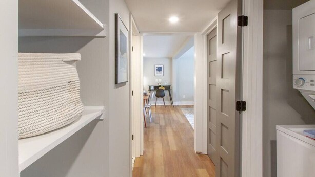 A hallway with a white shelf, a framed picture, a dining area with chairs and a table, and a washing machine. - Spacious & Peaceful-  Historic Franklin Quadplex (Franklin)