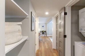 A hallway with a white shelf, a framed picture, a dining area with chairs and a table, and a washing machine. - Spacious & Peaceful-  Historic Franklin Quadplex (Franklin)