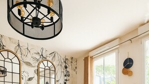 A living room with a sofa, a coffee table, a chandelier, and a wall with a leaf pattern.