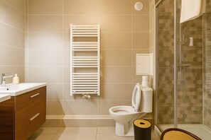 A modern bathroom with a toilet, a shower, and a towel rack. - Le Plessis-Capitale: Apartment with a private garden (Le Plessis-Robinson)