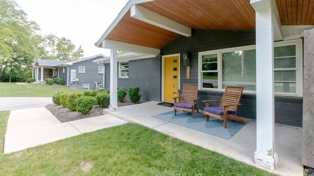 A modern two-story house with a covered porch, a yellow door, and two wooden chairs with cushions. - Pretty & Bright - Historic Franklin Quadplex (Franklin)