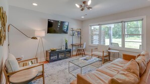 A spacious living room with a large window, a flat-screen TV, a sofa, and a coffee table. - Pretty & Bright - Historic Franklin Quadplex (Franklin)