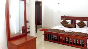 A bedroom with a wooden bed, a mirror, and a wooden dresser. - The Cave Kithulgala (Kithulgala)