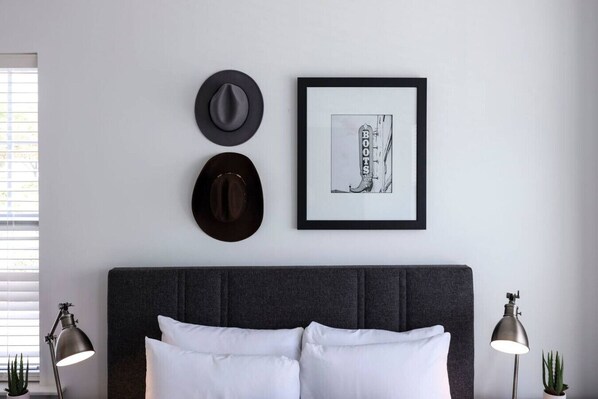 Ein ordentlich eingerichtetes Schlafzimmer mit einem großen Bett, zwei Wandhüten, einem gerahmten Bild und zwei Nachttischlampen.