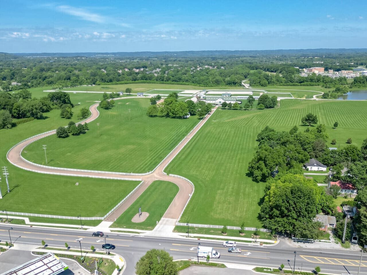 An aerial view of a large, green, open area with a winding track, surrounded by trees and buildings.