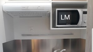 Une petite cuisine équipée comprenant un four à micro-ondes, un évier et des tiroirs de rangement.