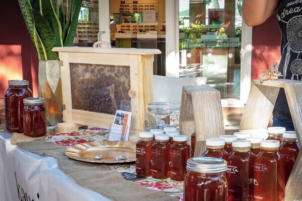 Een displaytafel met potten honing, een lijst met foto en houten bakken, waarschijnlijk op een markt of in een winkel.