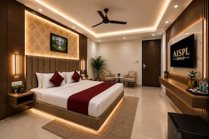 A modern hotel room with a large bed, a flat-screen TV, a ceiling fan, and a reception desk. - Airport Hotel Platinum (New Delhi)
