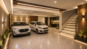A modern interior with a staircase, two white cars parked in a garage, and a well-lit hallway.