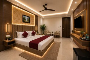 Une chambre d’hôtel moderne dotée d’un grand lit, d’un ventilateur de plafond, d’une télévision, d’un bureau et d’un coin salon avec deux fauteuils.