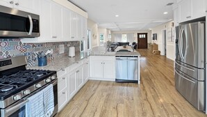 A modern kitchen with white cabinets, stainless steel appliances, and a patterned backsplash.