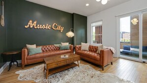 A modern living room with a leather sofa, a wooden coffee table, and a cowhide rug. A neon sign reads "Music City" on the wall.