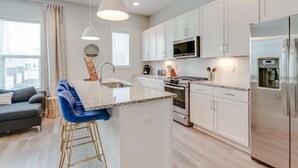 A modern kitchen with white cabinets, stainless steel appliances, and a central island with bar stools.